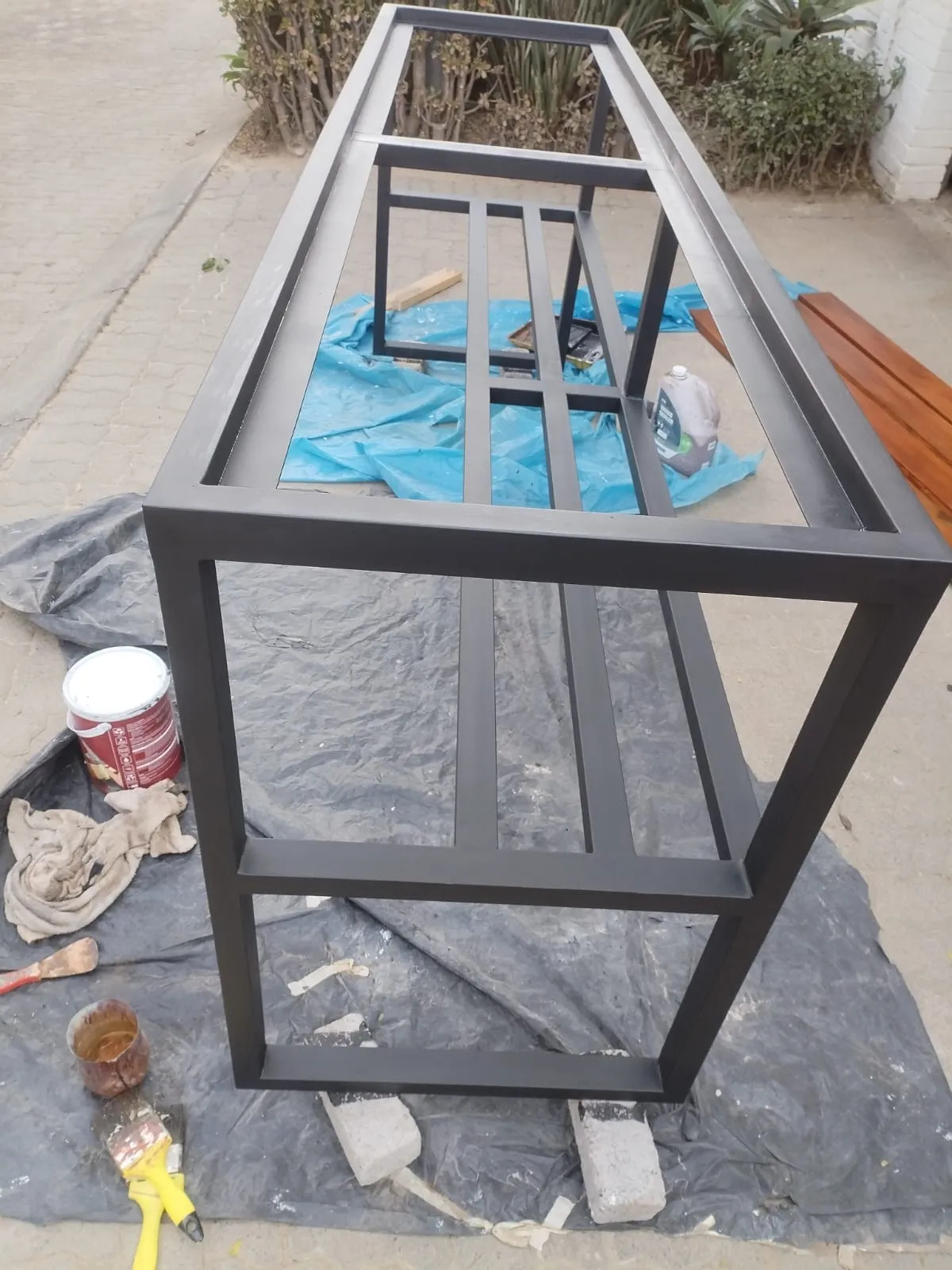 The steel frame painted matt black on a dropsheet, with the stained timber top alongside ready to fit