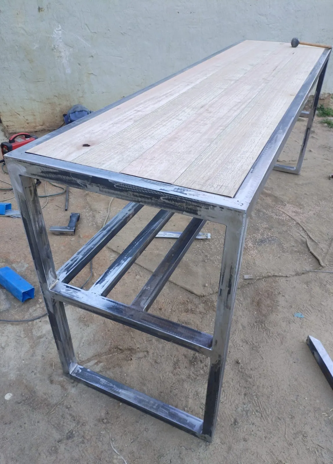 Bare steel frame with the raw hardwood top laid in, showing the recessed lip the timber sits into