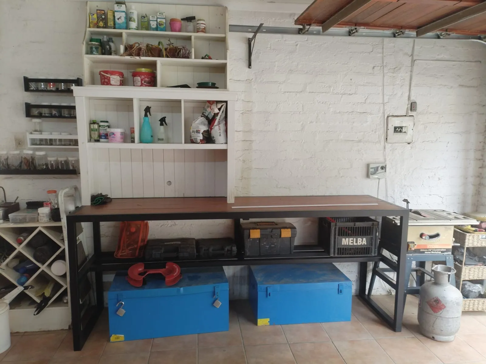 The console table in use along a workshop wall, holding toolboxes on its lower shelf