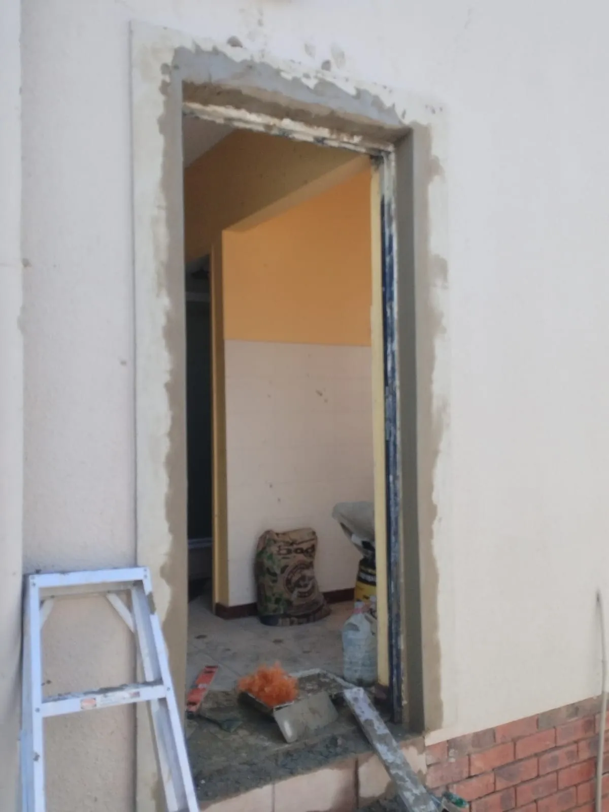 External doorway with the old frame removed, the reveal stripped back to brick and plaster ready for a new frame