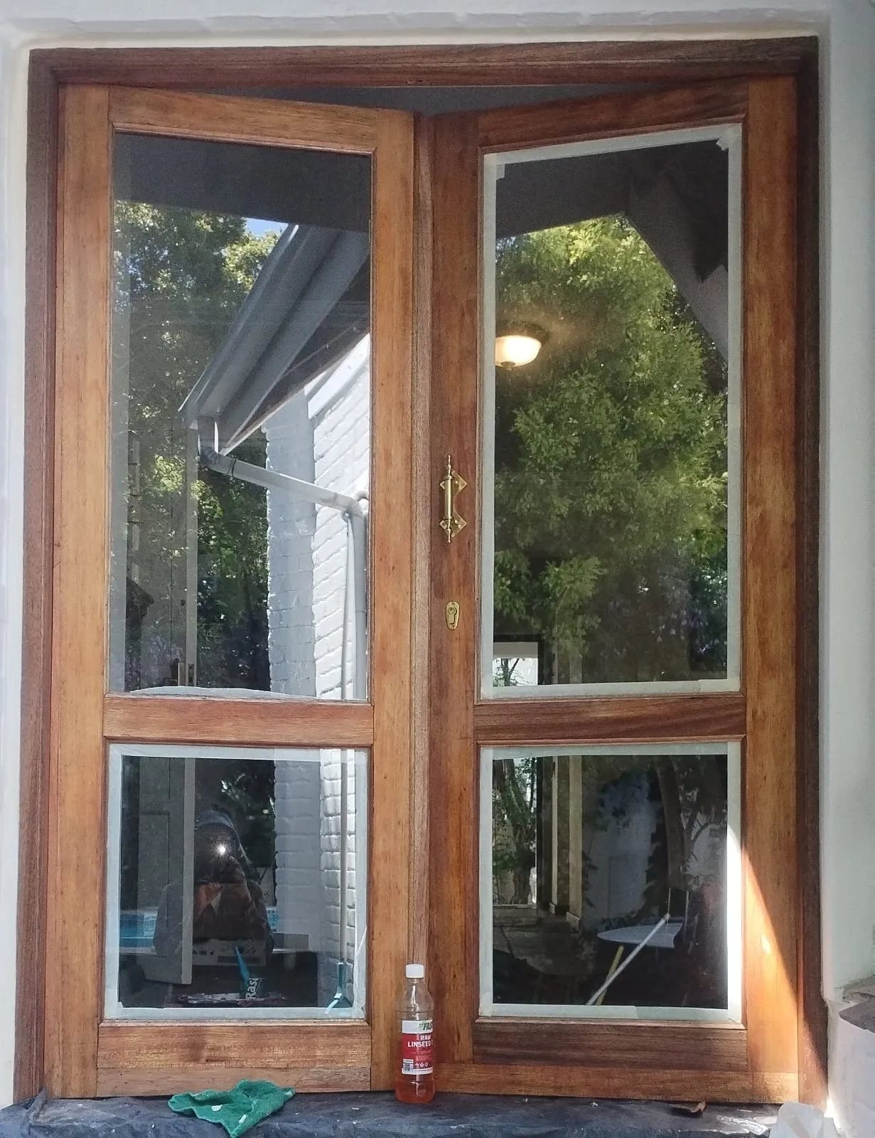 Close view of the doors mid-restoration, showing the patchy, weathered timber before the final coats went on