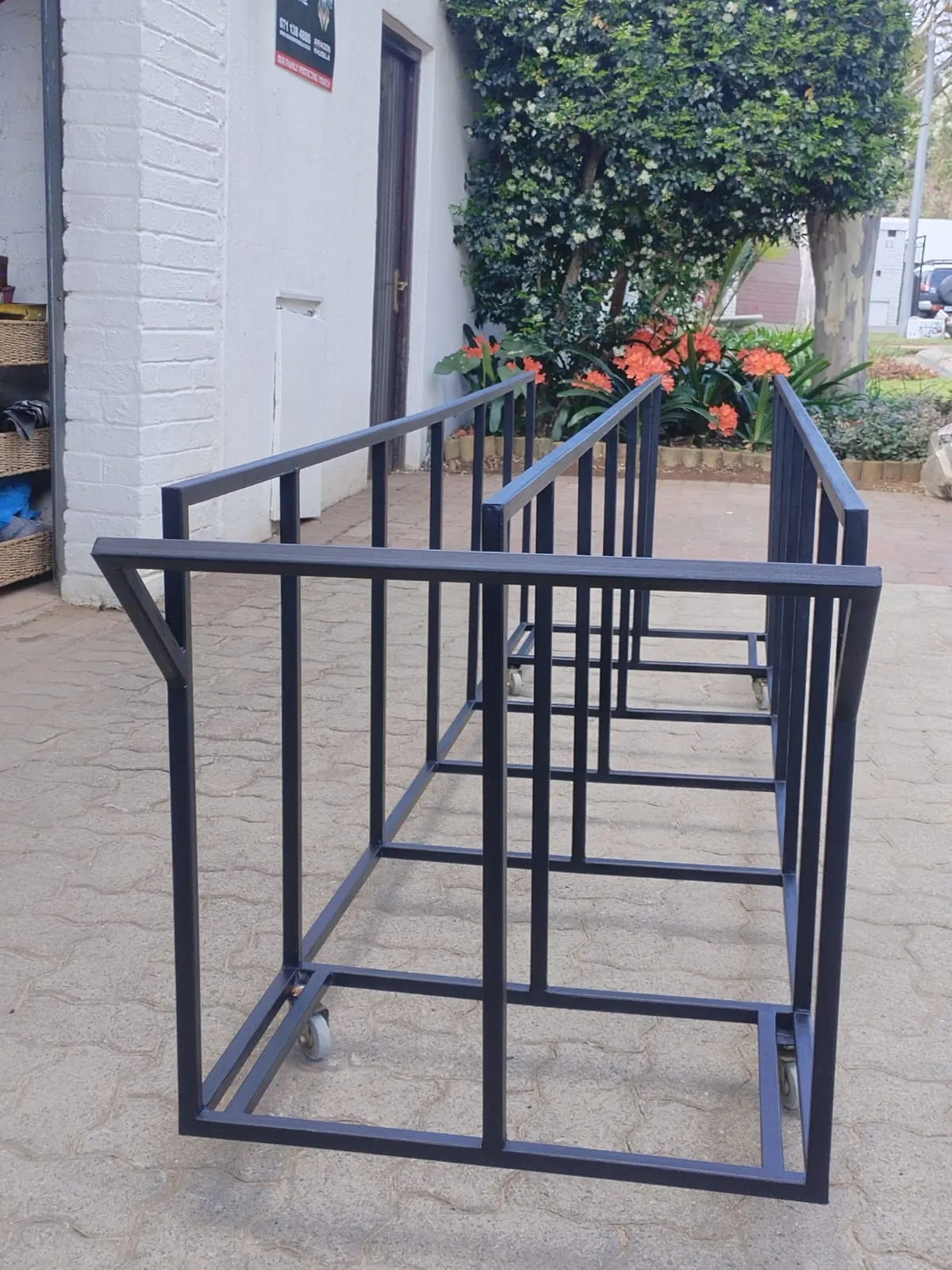 Black steel trolley rack on castors with divided vertical bays for sheet material